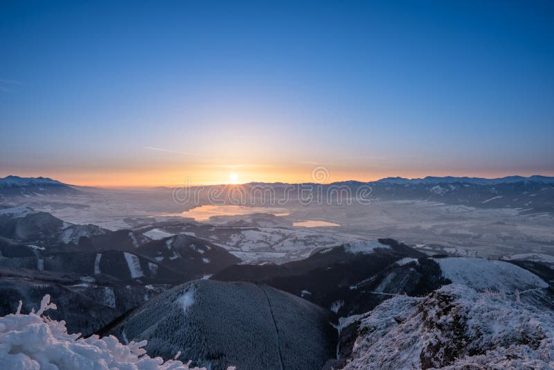 Zasnežená krajina východ slnka z Veľkého Choča v zime, s výhľadom na Nízke a Vysoké Tatry a Liptovskú Maru,