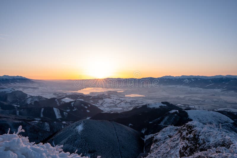 Zasnežená krajina východ slnka z Veľkého Choča v zime, s výhľadom na Nízke a Vysoké Tatry a Liptovskú Maru, slovensko