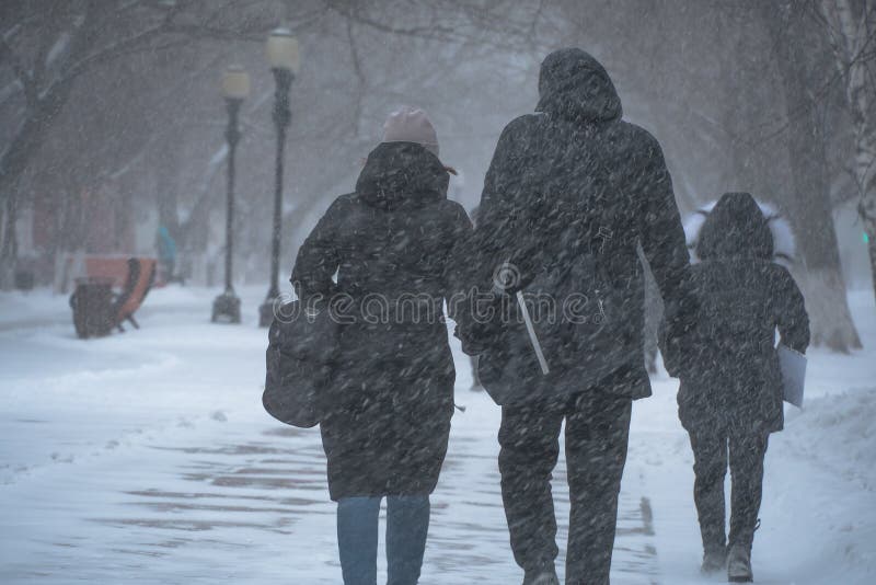 A snow-covered road with people in a storm,blizzard or snowfall in winter in bad weather in the city.Extreme winter weather