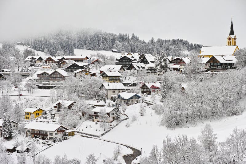 Vista dalla periferia alla città di Oberstaufen, riccamente ricoperto di neve, con la nebbia scendendo al bordo della foresta.
