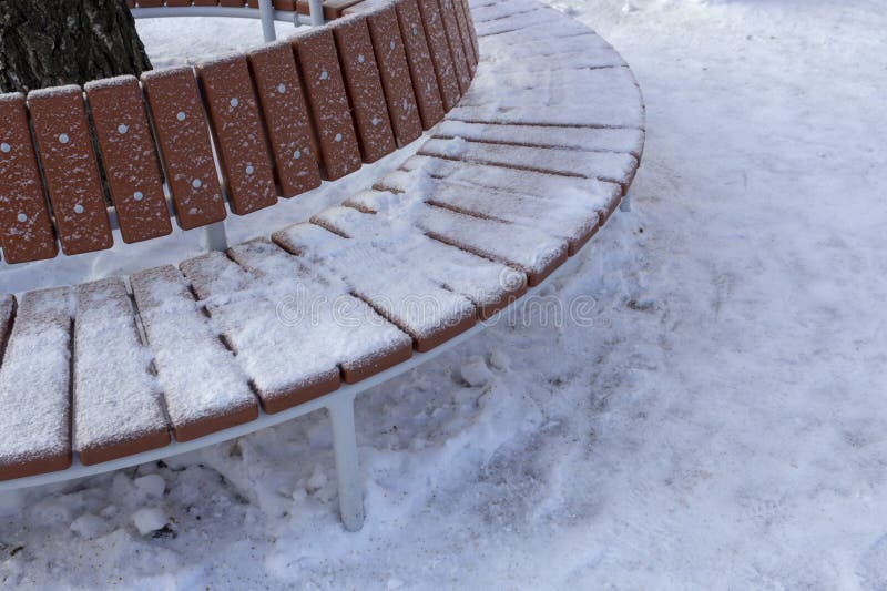 Snow-covered round bench around the tree royalty free stock image