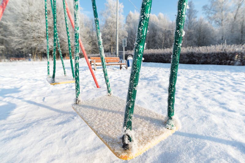 Snow covered swing and slide at playground in