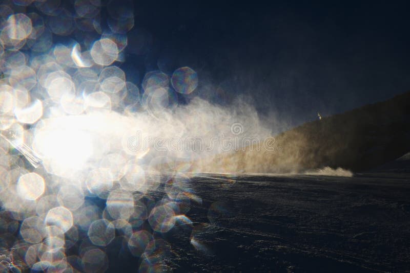 Snow making on slope. Skier near a snow cannon making fresh powder snow. Mountain ski resort and winter calm mountain landscape. Snow making on slope. Skier near a snow cannon making fresh powder snow. Mountain ski resort and winter calm mountain landscape.