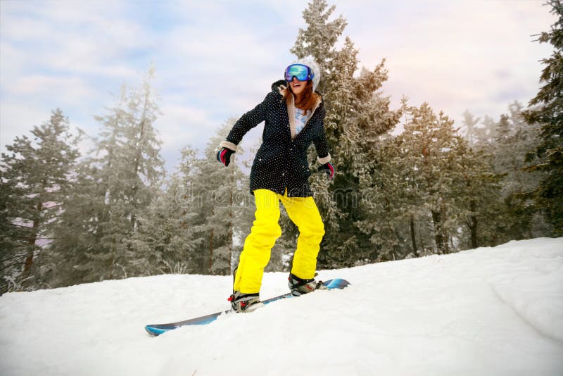Snowboarder da menina no salto na estância de esqui no inverno e da montanha imagem de stock Snowboarder da menina no salto na estância de esqui no inverno e da montanha imagem de stock