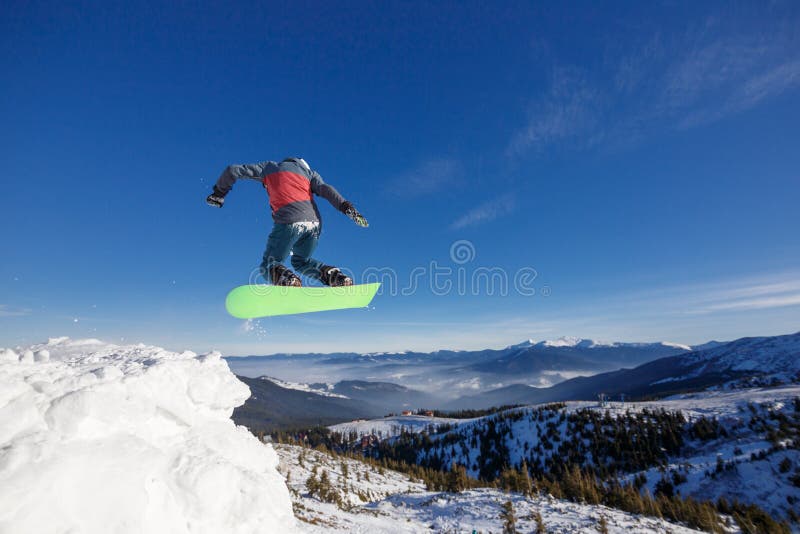 Snowboarder de salto en montañas en estación de esquí en el fondo Dragobrat del cielo azul imagenes de archivo Snowboarder de salto en montañas en estación de esquí en el fondo Dragobrat del cielo azul imagenes de archivo