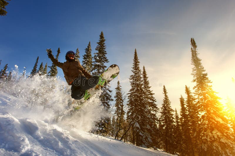 Snowboarder di salto sullo snowboard in montagne nella stazione sciistica