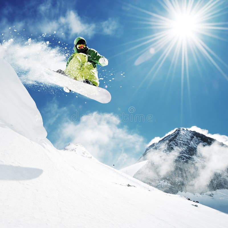 Snowboarder na skok inhigh hory v slnečný deň.