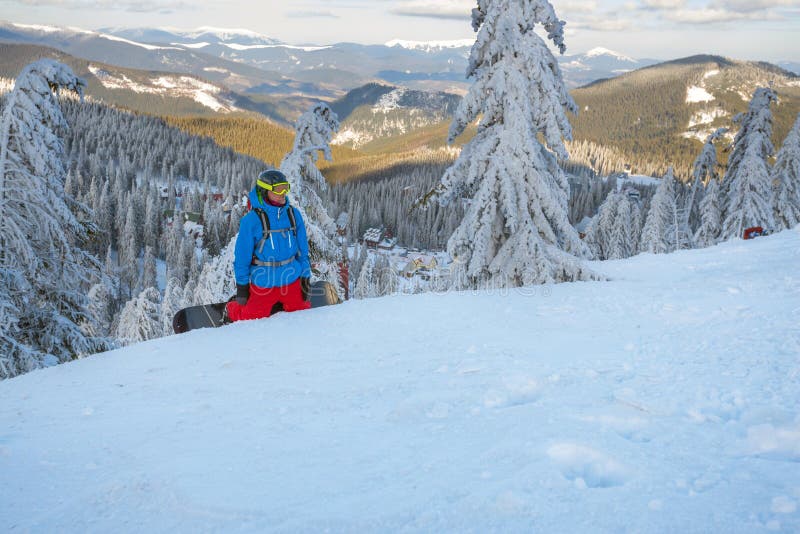 Snowboarderen vilar under en freeride, sitter på en berglutning, bland snö-täckte granträd, efter en häftig snöstorm och beundrar bergen Episk freeride i berg för en vinter