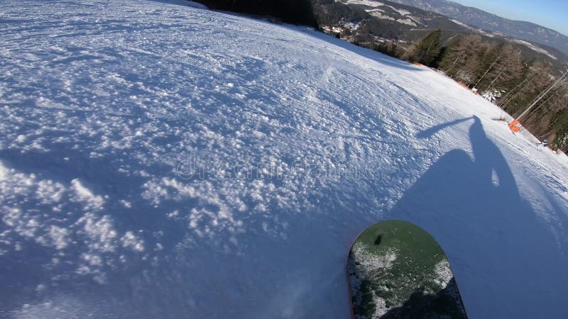 Snowboarderverschiebung auf einem Snowboard, den sein Schatten vor ihm auf dem Schnee synchron bewegt sich