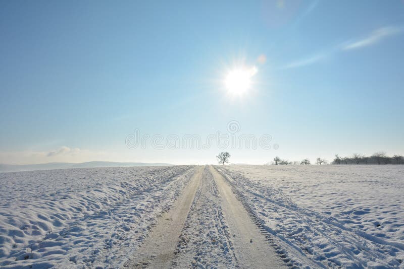 Snowcovered дорога в стране много снега в областях с небом и солнцем стоковые изображения rf