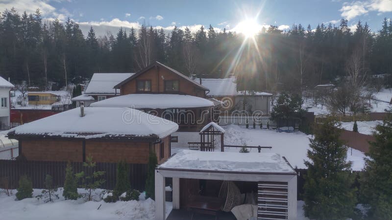 After a snowfall, everything is covered with snow. Against the background of the forest towering buildings with snow-covered roofs stock image