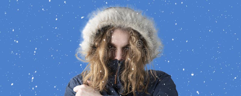 Snowfall. Winter. A person freezes in cold weather. A man in a winter jacket is standing on the street stock photography