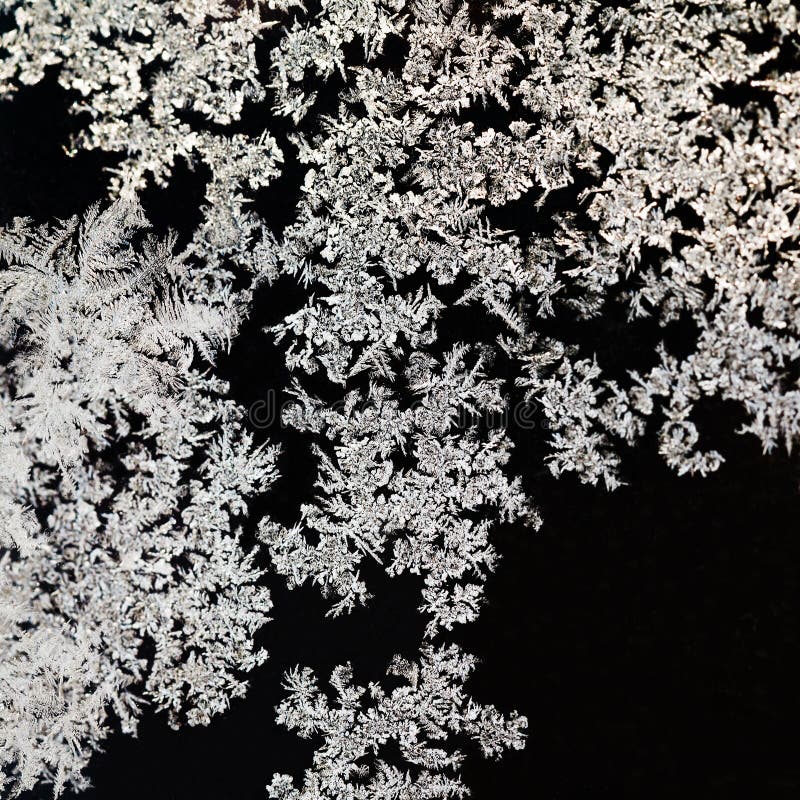 Snowflakes and frost pattern on glass close up