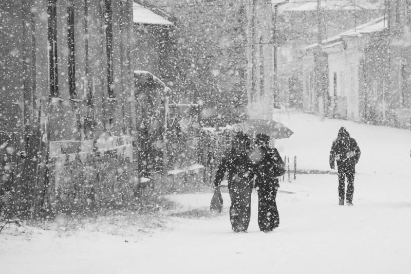 Snowing urban landscape with people passing by