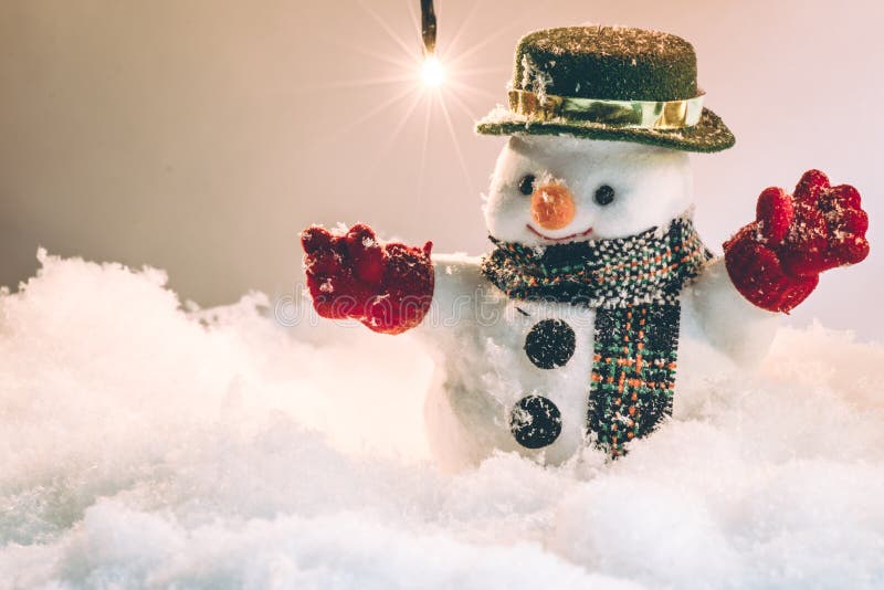 Snowman and snow is falling down, stand among pile of snow at silent night with a light bulb