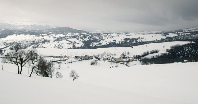 Snowy fields and mountains, and a little rural town stock image