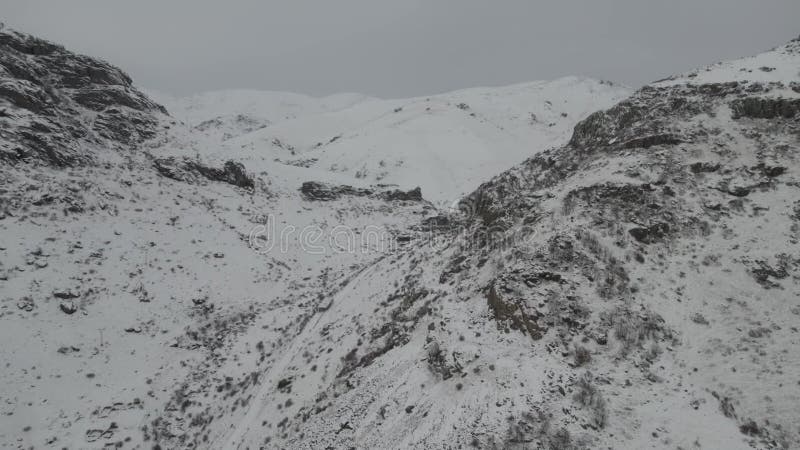 Snowy mountain landscape with a deep valley, covered in fresh snow under an overcast sky stock video footage