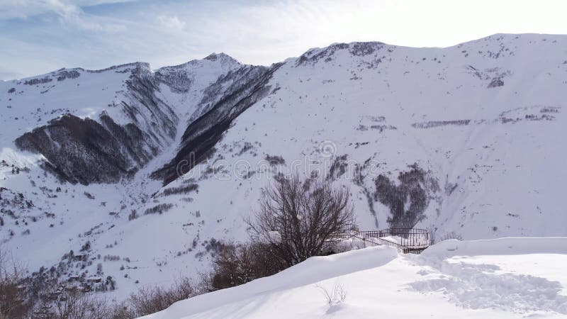 Snowy mountain landscape with a prominent peak covered in fresh snow under a partly cloudy sky stock video footage