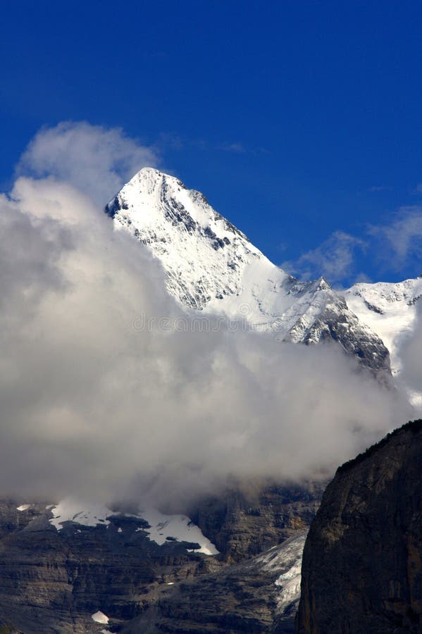 Snowy mountain top with clouds and sunny blue sky