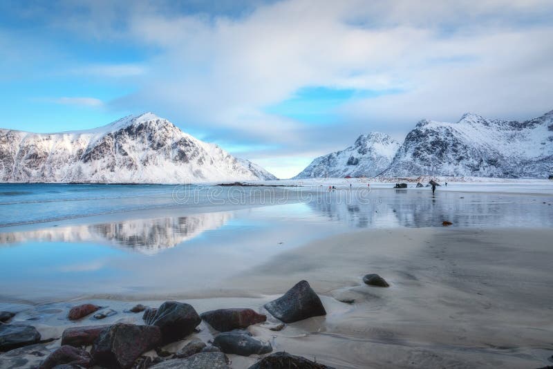 Snowy mountains and blue sky with clouds reflected in water