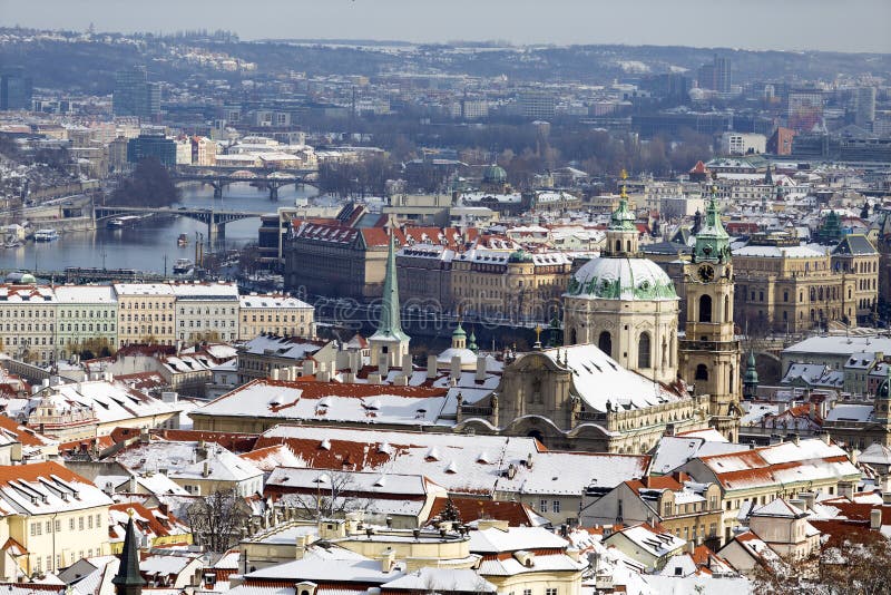 Snowy Prague City with St. Nicholas` Cathedral from Hill Petrin in the sunny Day, Czech republic