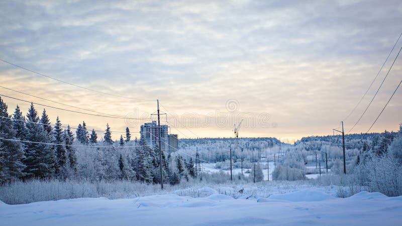 Snowy road, forest and construction site on winter landscape