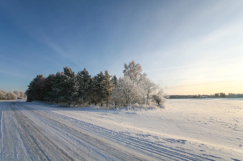 Snowy und eisige, leere Landschaftswinterstraße bei Sonnenuntergang lizenzfreies stockbild