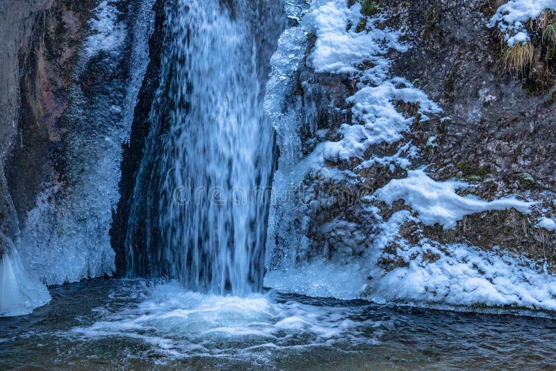 Zasněžená zimní krajina s vodopádem na divokém potoku