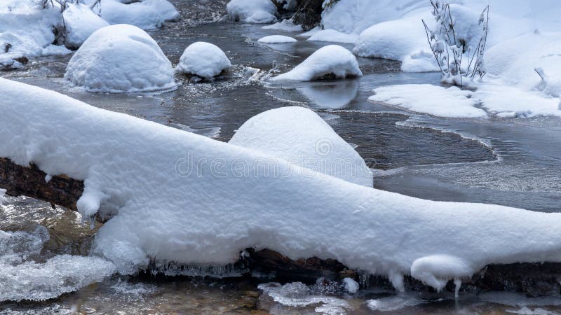 Zasněžená zimní krajina s divokým potokem