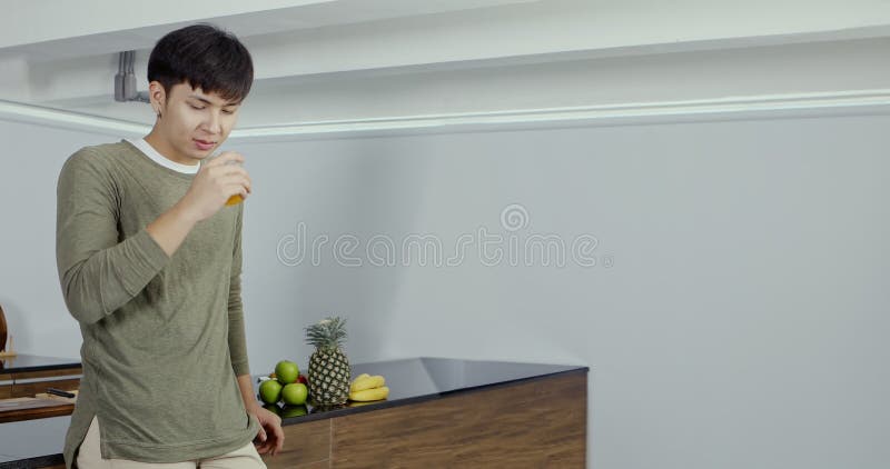 Snygg asiatisk man som dricker apelsinjuice. lager videofilmer