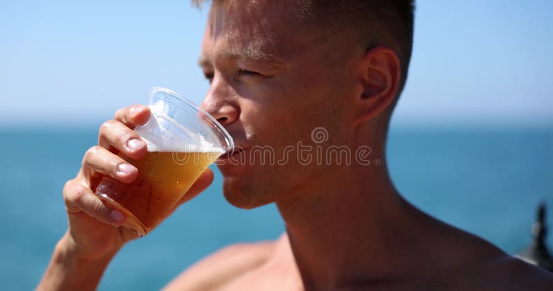 Snygg man dricker kallt öl på stranden stock video