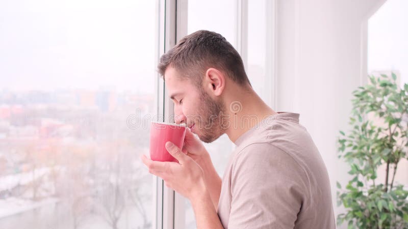 Snygg man som dricker kaffe och ser fönster lager videofilmer