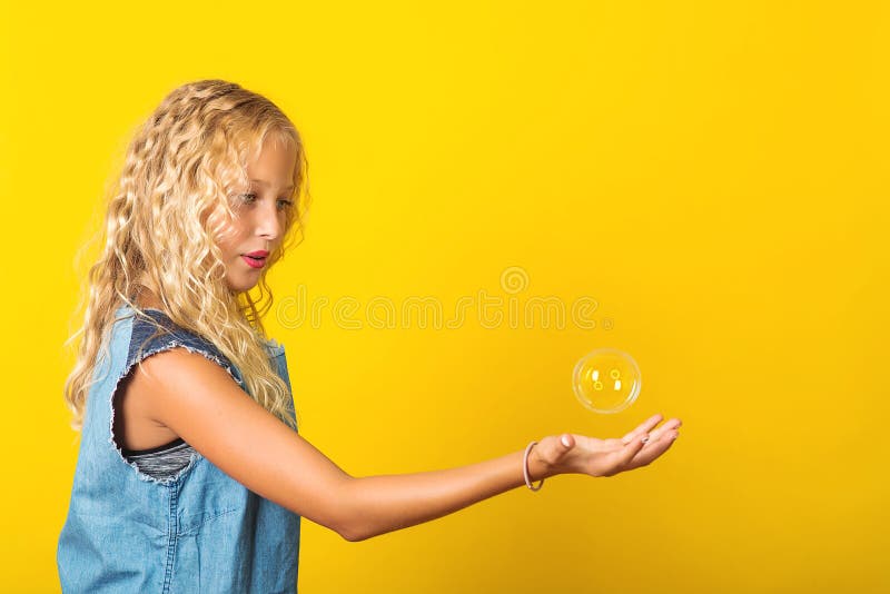 Snygg tjej får tvålbubbla över gul bakgrund Blonde flicka med frisk hår Sommarmode royaltyfri fotografi Snygg tjej får tvålbubbla över gul bakgrund Blonde flicka med frisk hår Sommarmode royaltyfri fotografi