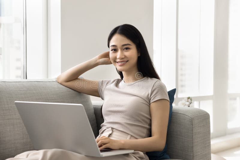 Snygg, ung asiatisk kvinna tillbringar heltidsfritid med modern bärbar dator royaltyfri fotografi