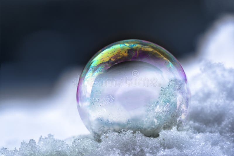 Soap bubble with rainbow reflections in the snow, winter still l royalty free stock photo