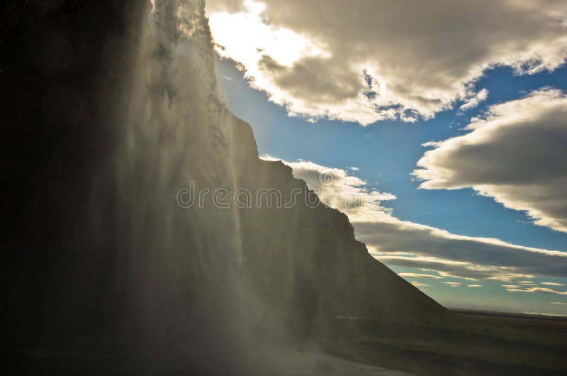 Sob a cachoeira de Seljalandsfoss do rio Seljalandsa, Islândia sul fotografia de stock royalty free Sob a cachoeira de Seljalandsfoss do rio Seljalandsa, Islândia sul fotografia de stock royalty free