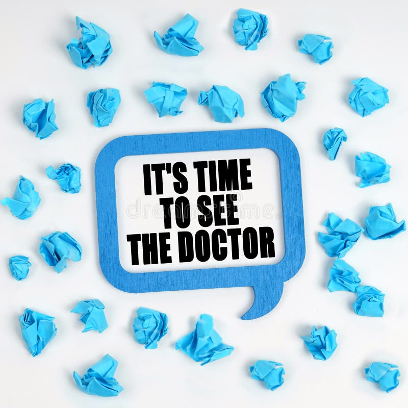 Sobre la mesa hay trozos de papel azules desmoronados y un plato de reflexión con la inscripción es el momento de ver al médico foto de archivo