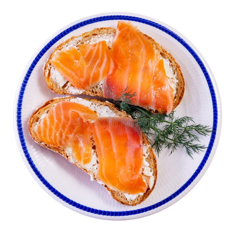 On top of greased bread is slice of lightly salted salmon decorated with dill. Two sandwiches, snack. Isolated over white background. On top of greased bread is slice of lightly salted salmon decorated with dill. Two sandwiches, snack. Isolated over white background