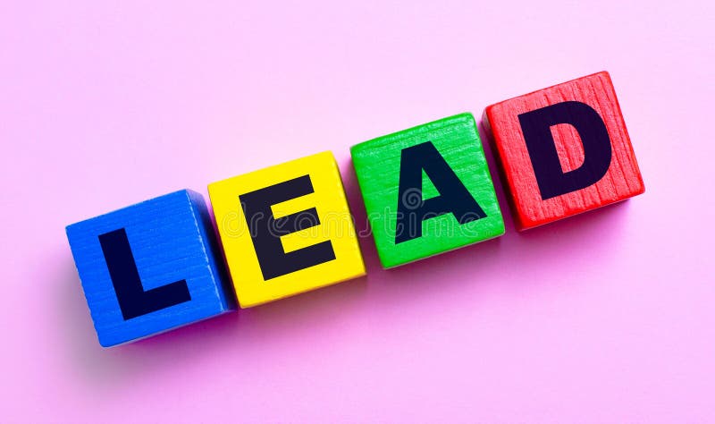 Sobre um fundo cor-de-rosa claro, cubos de madeira multicoloridos com chumbo de texto imagem de stock