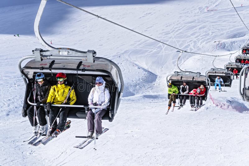 Soci, Russia - 20 gennaio 2013: Gli sciatori e gli snowboarders guidano sull'ascensore di sci della sedia il giorno di inverno so fotografia stock libera da diritti Soci, Russia - 20 gennaio 2013: Gli sciatori e gli snowboarders guidano sull'ascensore di sci della sedia il giorno di inverno so fotografia stock libera da diritti