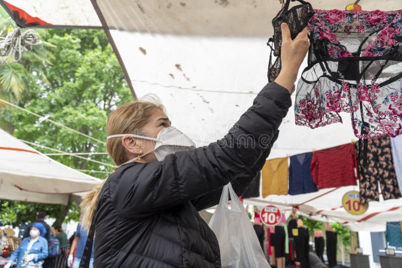 Social distance after Covid-19 lock down. A street market selling clothes and textile. Shopping people wearing medical face