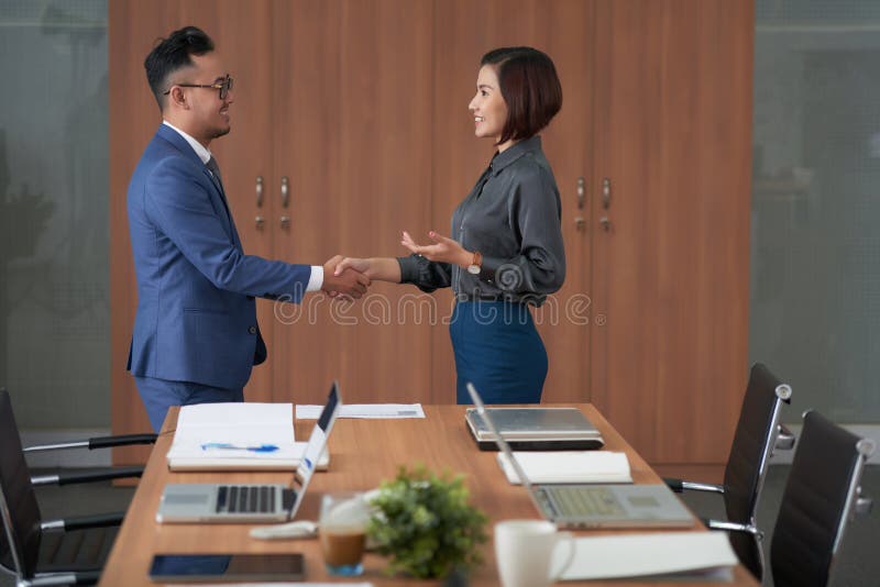 Socios comerciales que sacuden las manos en la oficina imagen de archivo
