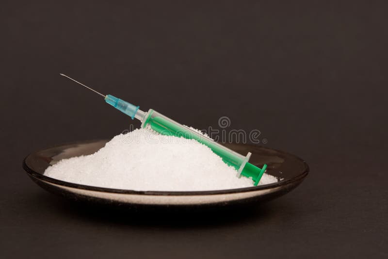 Disposable syringe on a small pile of sugar with copy space - for concepts like diabetes or insulin. Disposable syringe on a small pile of sugar with copy space - for concepts like diabetes or insulin