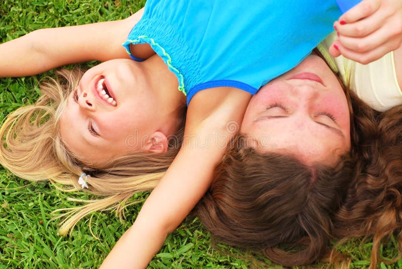 Two caucasian sisters playing and laughing in the grass. Two caucasian sisters playing and laughing in the grass