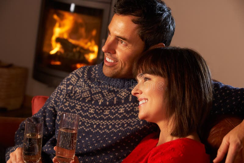 Sofa se reposant âgé moyen de couples par le feu de bois confortable image libre de droits Sofa se reposant âgé moyen de couples par le feu de bois confortable image libre de droits
