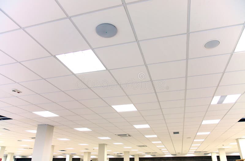Soffitto bianco dell'ufficio con le mattonelle bianche e l'illuminazione