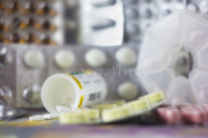Soft blurred background with pills of various colors and shapes in blister pack, pill case, plastic jar.