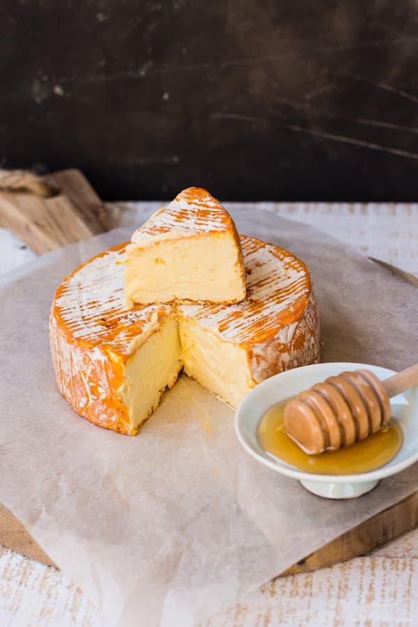 Soft cheese with cut off slice creamy texture, orange rind with mold, French, German,top view, rustic kitchen interior royalty free stock photography