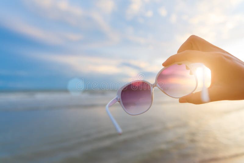 Soft focus on woman hand holding sunglasses over sea and Sandy stock photography Soft focus on woman hand holding sunglasses over sea and Sandy stock photography