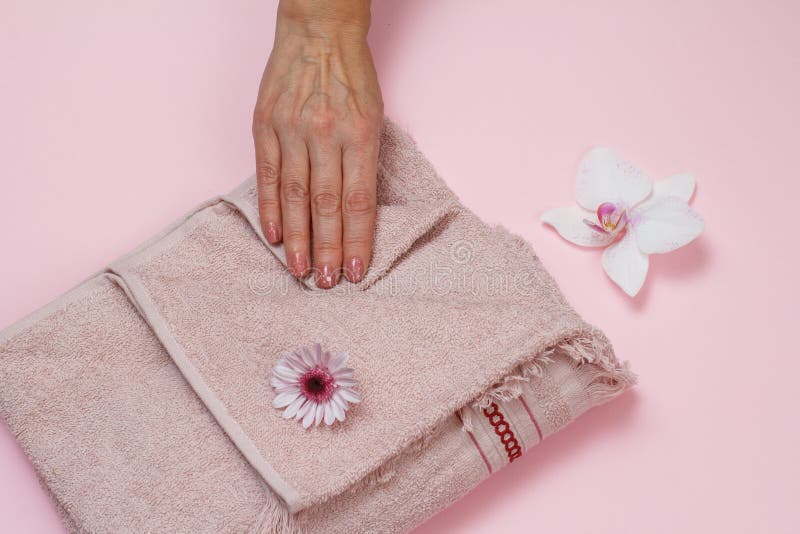 Soft terry towel with hand and flowers on pink background royalty free stock photos